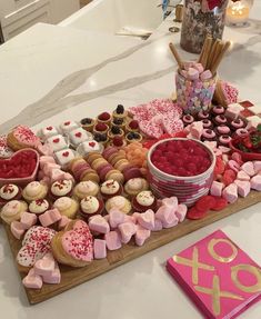 a table topped with lots of cupcakes and other desserts next to a pink book