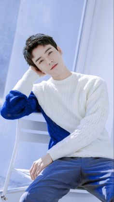 a young man sitting on top of a white chair