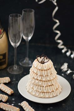 a cake with white icing and chocolate on top next to wine glasses, confetti sticks and streamers