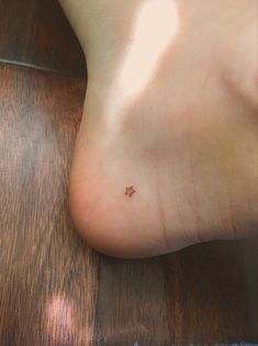 a person's foot with a tiny star tattoo on it