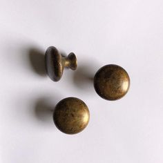 three brass knobs on a white surface