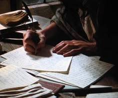 a person sitting at a table with lots of papers and pens in front of them