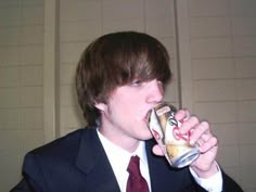 a man in a suit drinking from a can