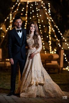 a man and woman in formal wear standing next to each other with lights on the background