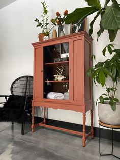 an orange cabinet sitting next to a black chair and potted plant on top of it