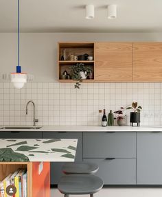 a kitchen with grey cabinets and stools next to a counter top that has books on it