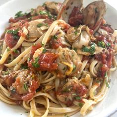 a white plate topped with pasta and clams