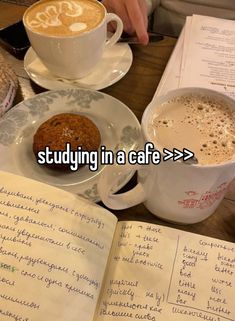 someone is studying in a cafe while holding a cup of coffee and an open book