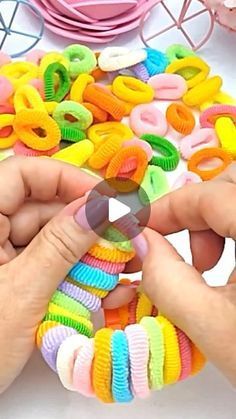 two hands are holding colorful bracelets on a table