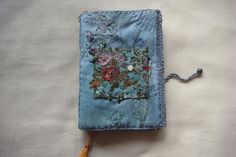 an embroidered book with tassels and flowers on it