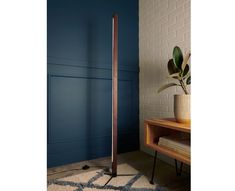 a wooden floor lamp next to a blue wall and a potted plant on a table