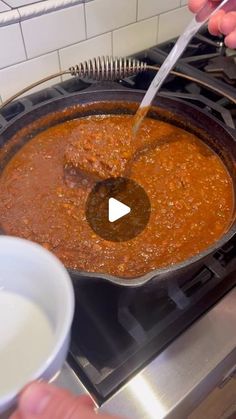 someone is stirring chili in a skillet on the stove