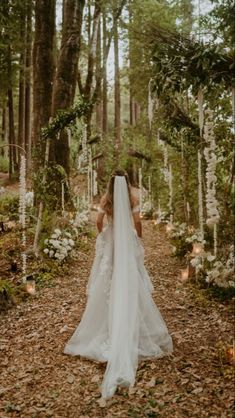 a woman in a wedding dress walking through the woods