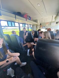 people sitting in seats on a bus looking at their laptops while others look on