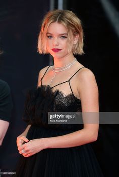 a woman in a black dress poses on the red carpet at an awards event,