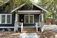 a small blue house with white trim and steps leading up to the front door,