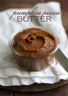 a glass bowl filled with peanut butter sitting on top of a white napkin next to a knife