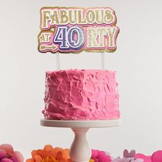 a pink birthday cake sitting on top of a table