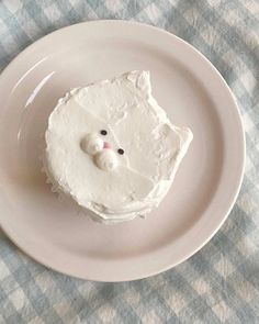 a white plate topped with a cake covered in frosting and a teddy bear face