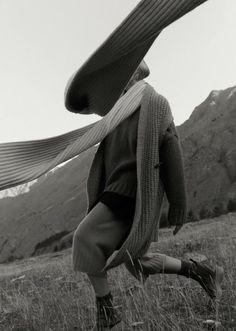 black and white photograph of a woman in the mountains carrying a large scarf over her head