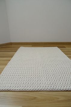 a white rug on the floor in front of a wall and wood flooring area