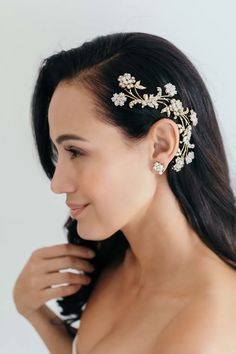 a woman in a white dress wearing a gold and crystal floral hair comb with pearls on it