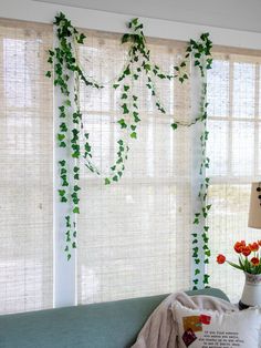 a living room filled with furniture and flowers on the window sill covered in vines