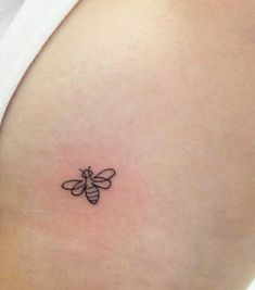 a small black and white bee tattoo on the back of a woman's stomach