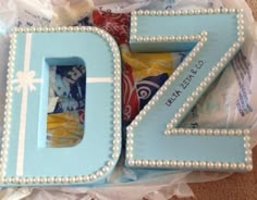 a cake shaped like the number twenty seven with pearls on it's edges and decorated in blue icing