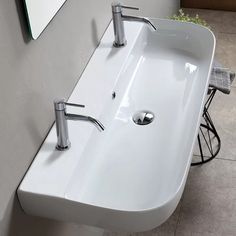 a bathroom sink with two faucets on the wall