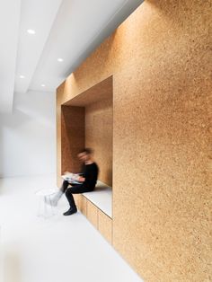 a person sitting on a bench in a room with wood paneling and white walls