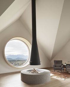 a living room with a large round window in the ceiling and a fire place on the floor