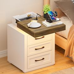 a nightstand table with a phone on it next to a bed