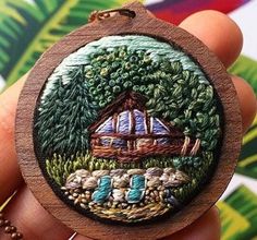 a hand holding a small wooden ornament with an image of a house on it