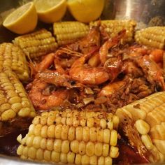 corn on the cob and shrimp in a pot with lemon wedges