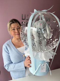 a woman is holding a stuffed animal in a clear box with pearls on the sides