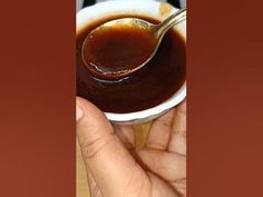 a hand holding a spoon full of sauce