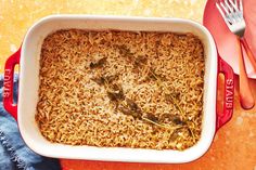 a casserole dish filled with brown rice and spinach garnished with silverware