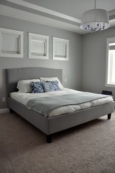 a large bed sitting in the middle of a bedroom next to a window with white shutters