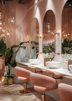 the interior of a salon with pink chairs, mirrors and lights on the wall behind them