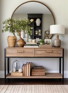 a table with books, vases and plants on it in front of a mirror