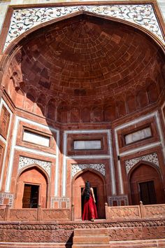 a woman in a red dress is standing on some steps and looking up at the ceiling