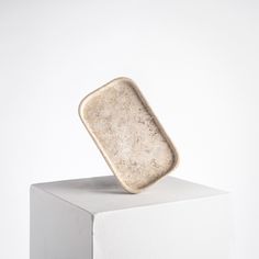 a square object sitting on top of a white block