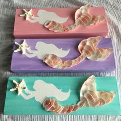 three little mermaids painted on wooden boards with shells and starfish in the background