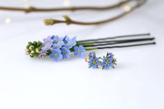 small blue flowers sitting on top of each other next to some chopsticks and twigs