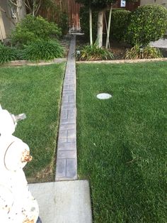 a fire hydrant sitting in the middle of a yard next to a sidewalk and trees