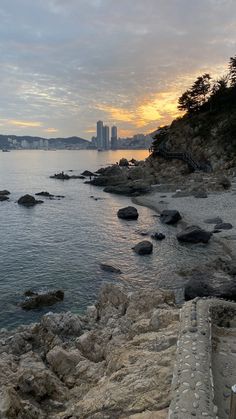 a bench sitting on top of a rocky beach next to the ocean