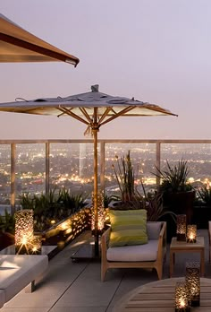 an outdoor seating area with umbrellas and lights on the roof terrace at night time