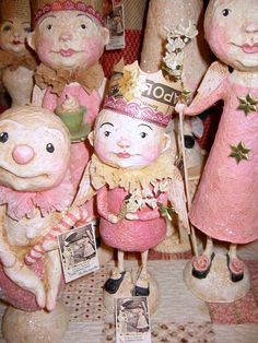 a group of ceramic figurines that look like children with hats and dresses, standing next to each other