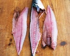 three pieces of fish sitting on top of a wooden cutting board